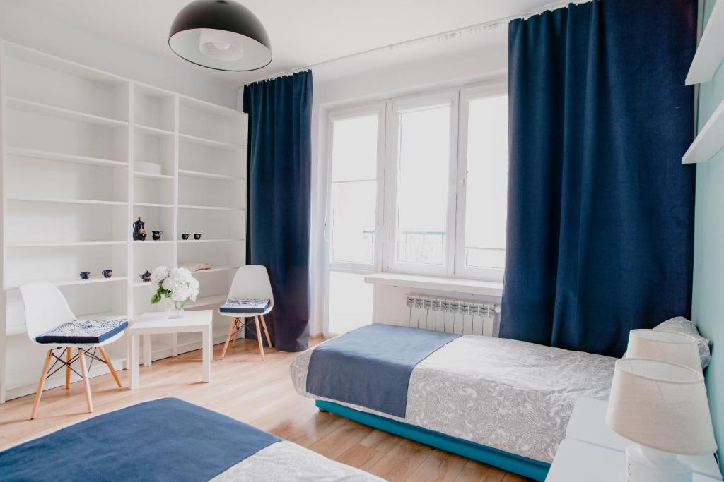 een slaapkamer met blauwe gordijnen, een bed en een bureau bij Prudentia Apartments Grenadierów in Warschau