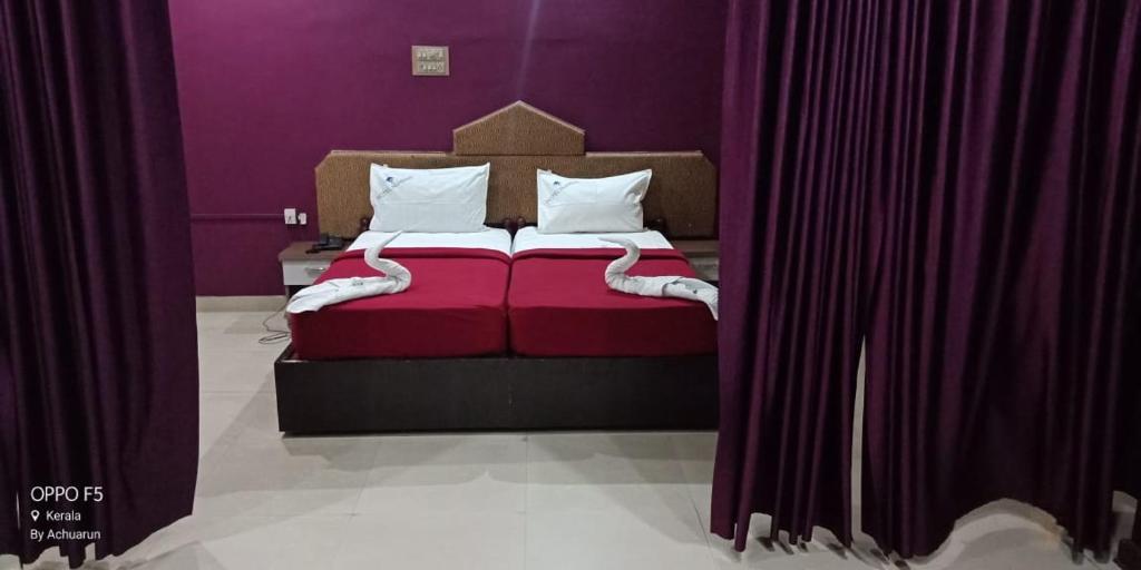 Un dormitorio con una cama roja con paredes moradas en Hotel Nuhman en Kondotti