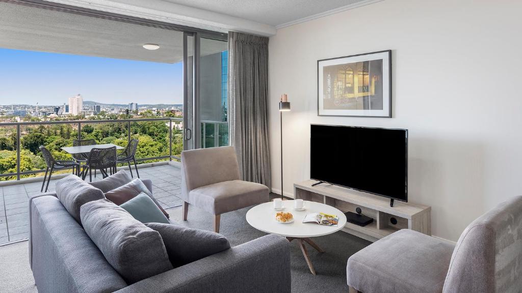 a living room with a couch and a flat screen tv at Oaks Brisbane on Margaret Suites in Brisbane