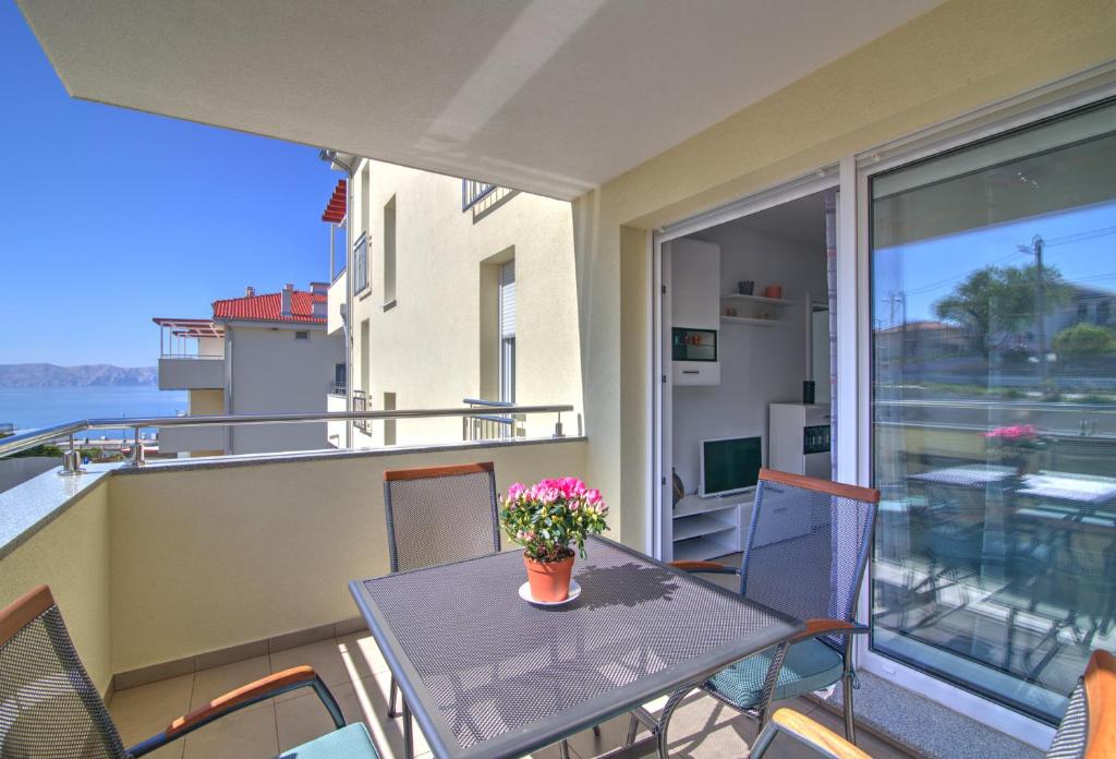 einen Tisch und Stühle auf einem Balkon mit einem Tisch und Blumen in der Unterkunft Apartment Waves-Villa Sunce in Senj