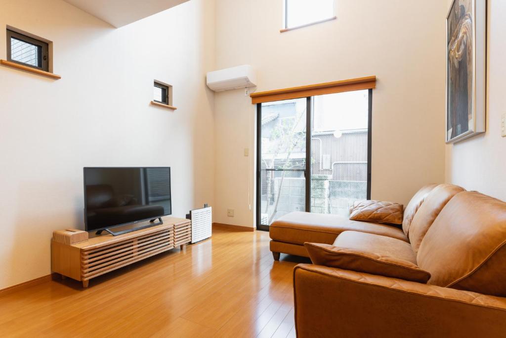 a living room with a couch and a flat screen tv at Ecol Beppu in Beppu