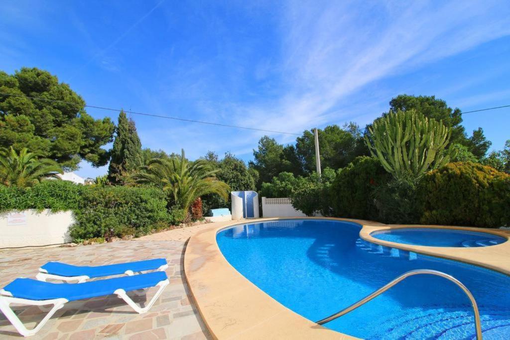 una piscina con 2 sillas azules al lado en Villa totalmente independiente con piscina comunitaria, en Calpe