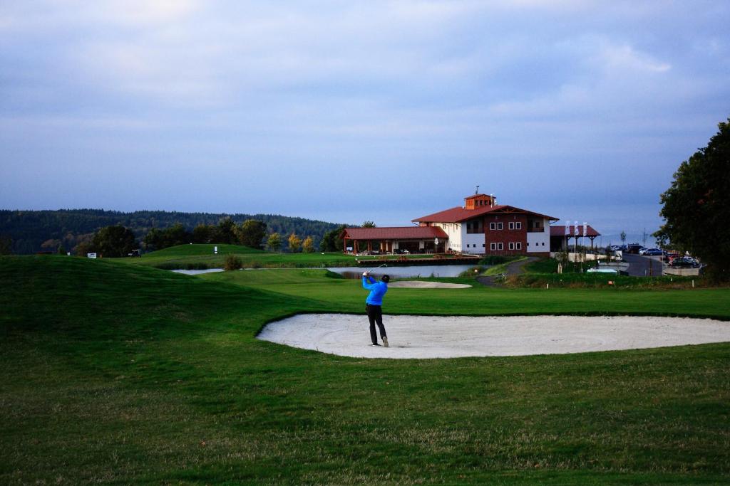Hotel Golf Resort Olomouc في Dolany: شخص يتأرجح في ملعب للجولف