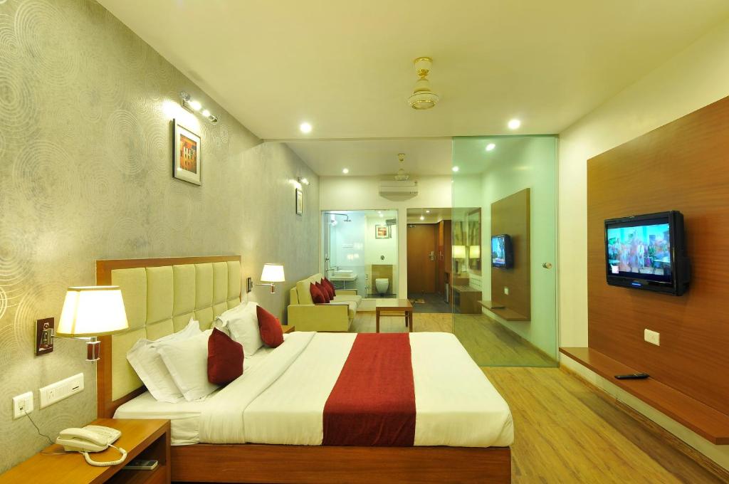 a hotel room with a large bed and a television at Hotel Aditya in Raipur