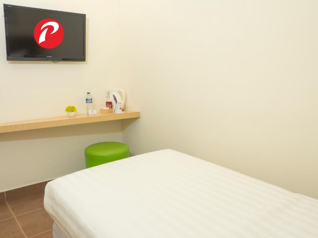 a bedroom with a white bed and a green chair at d'primahotel Airport Jakarta Terminal 1A in Tangerang