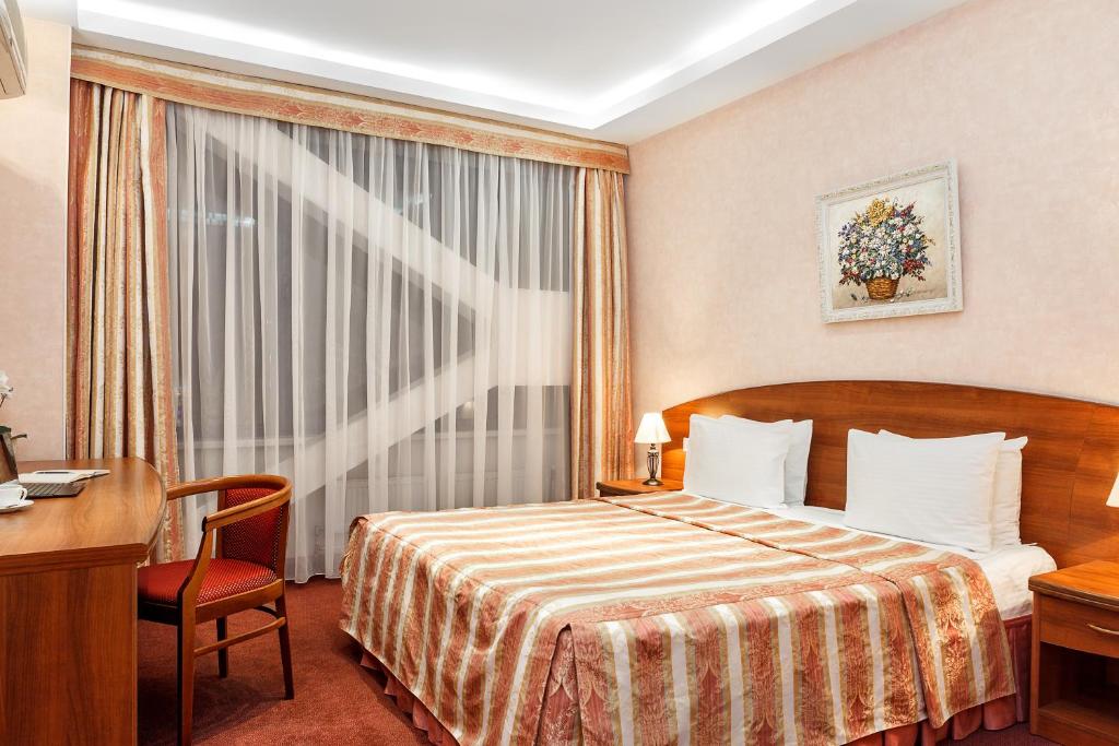a hotel room with a bed and a desk and a window at Hotel Nikol in Nizhny Novgorod