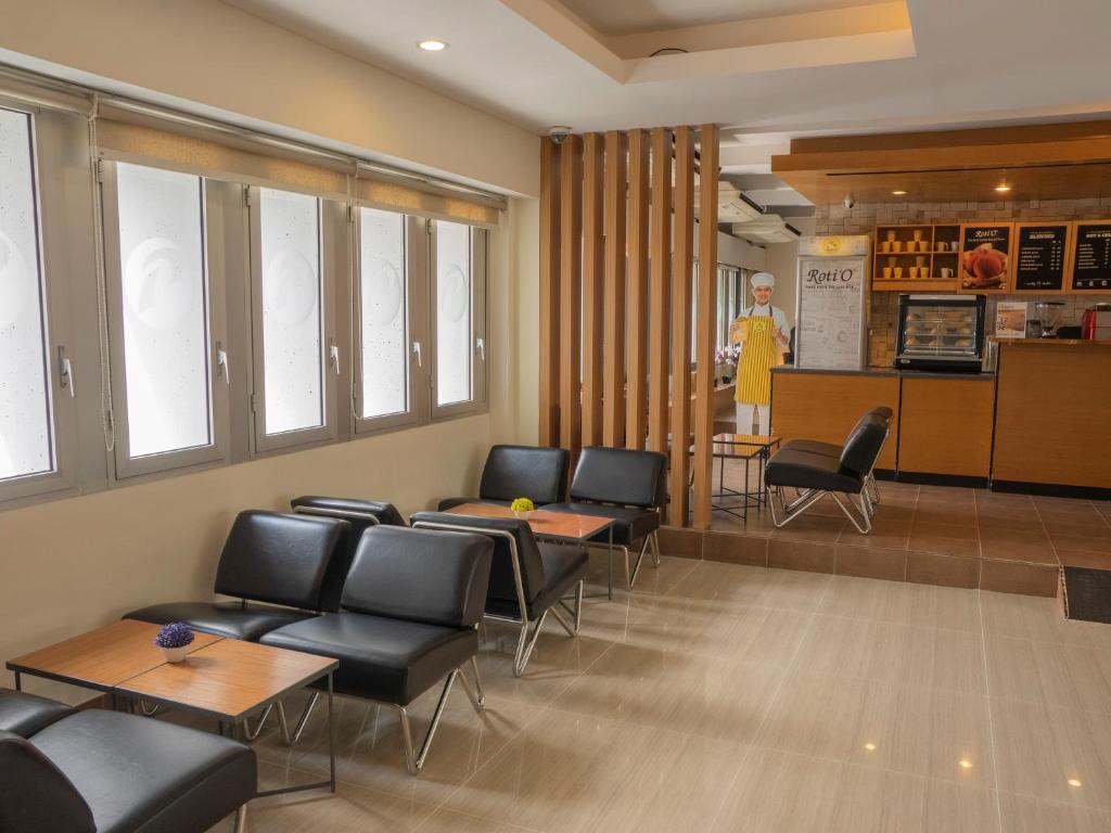 a waiting room with chairs and tables and a woman in a yellow dress at d'primahotel Airport Jakarta Terminal 1A in Tangerang