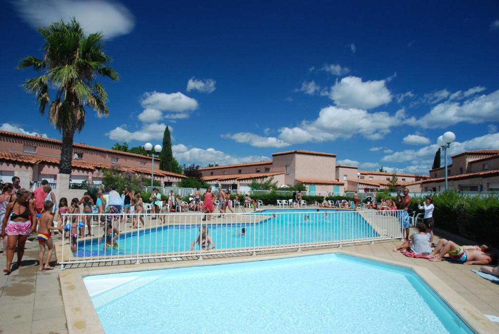 um grupo de pessoas em pé em torno de uma piscina em Lagrange Grand Bleu Vacances – Résidence Les Jardins de Neptune em Saint-Cyprien
