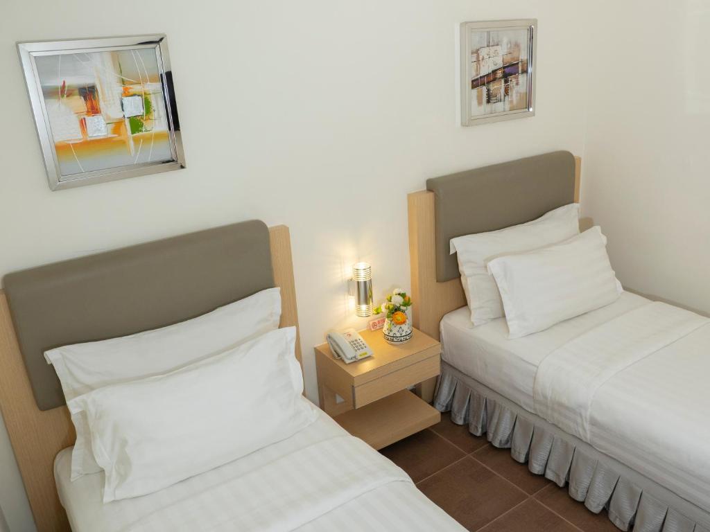 a hotel room with two beds and a night stand with a nightstand at d'primahotel Airport Jakarta Terminal 1A in Tangerang