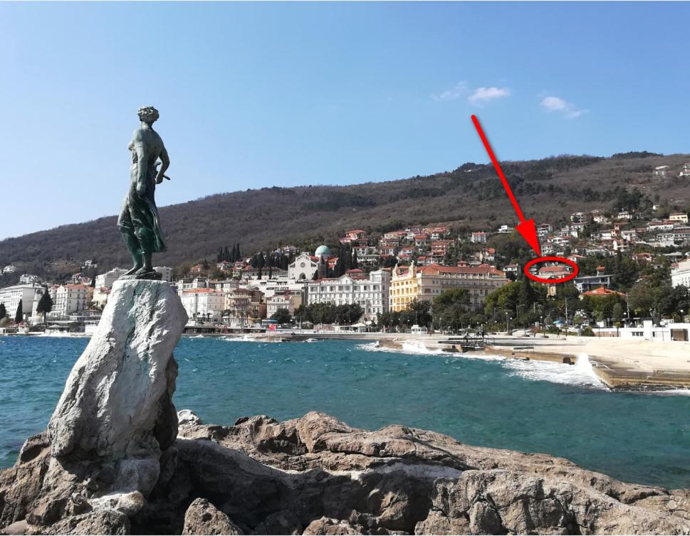 a statue on a rock in the water near a beach at Panoramico Apartment Opatija in Opatija