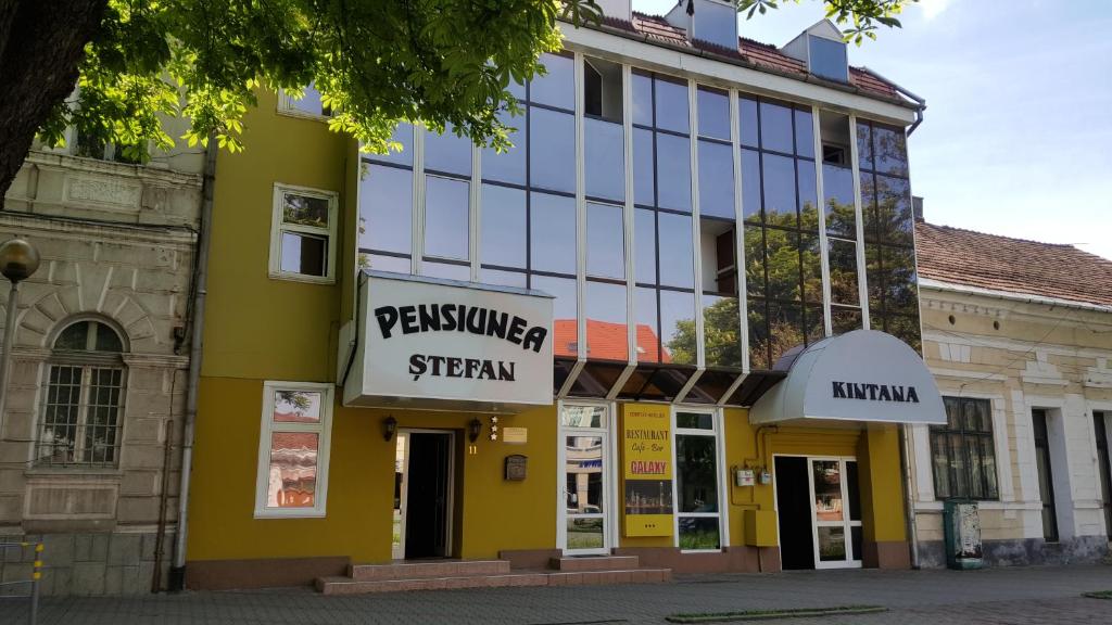 a yellow and white building with a sign on it at Pensiunea Stefan in Bistriţa