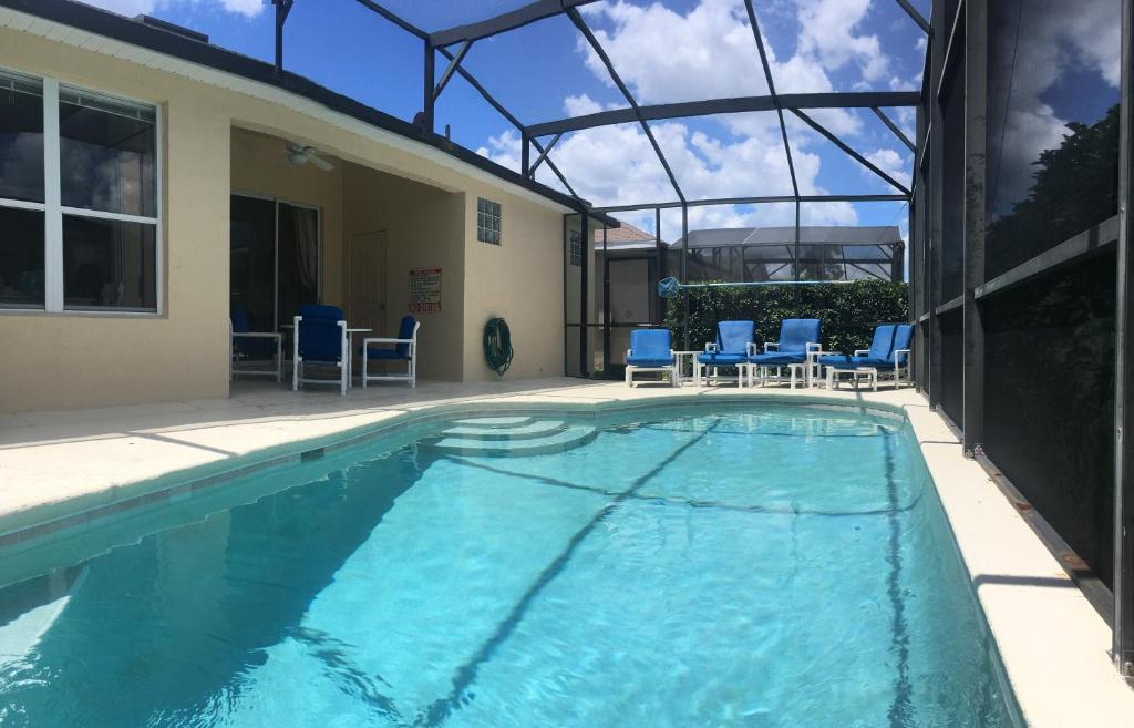 a swimming pool with blue chairs and a house at Mickey Holiday Home a Windsor Palms Villa in Kissimmee