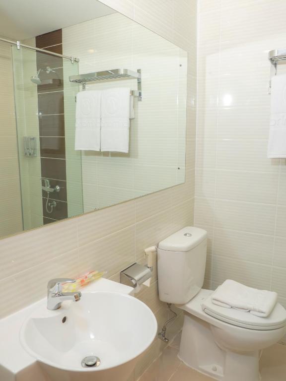 a white bathroom with a toilet and a sink at d'primahotel Airport Jakarta Terminal 1A in Tangerang