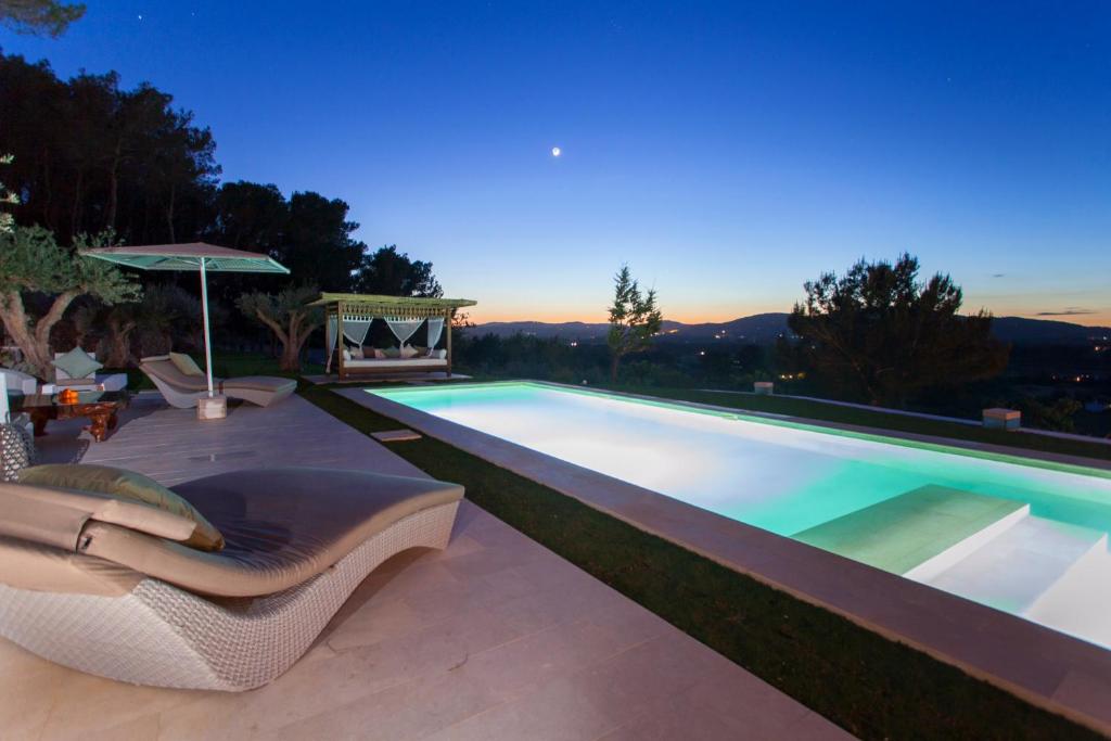 a swimming pool with two chairs and an umbrella at Ibiza luxury villa in Santa Eularia des Riu