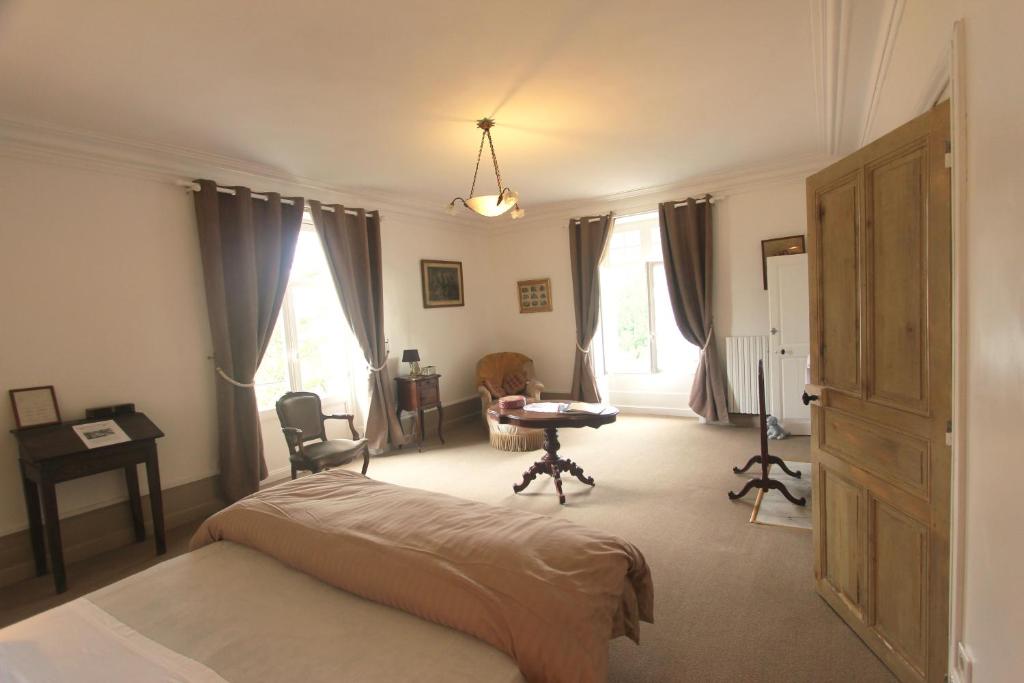 a bedroom with a bed and a desk and windows at Domaine de Planchoury in Saint-Michel-sur-Loire