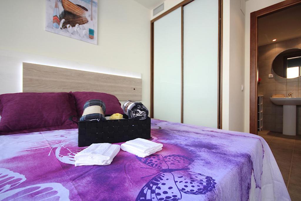 Una cama morada con toallas y una caja. en Romantic Loft, en Salàs de Pallars