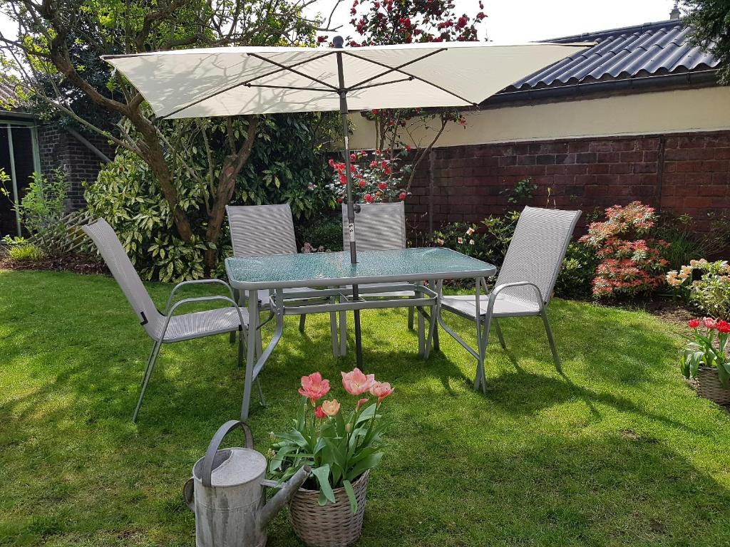 una mesa y sillas bajo una sombrilla en un patio en Les Bruyeres en Sotteville-lès-Rouen