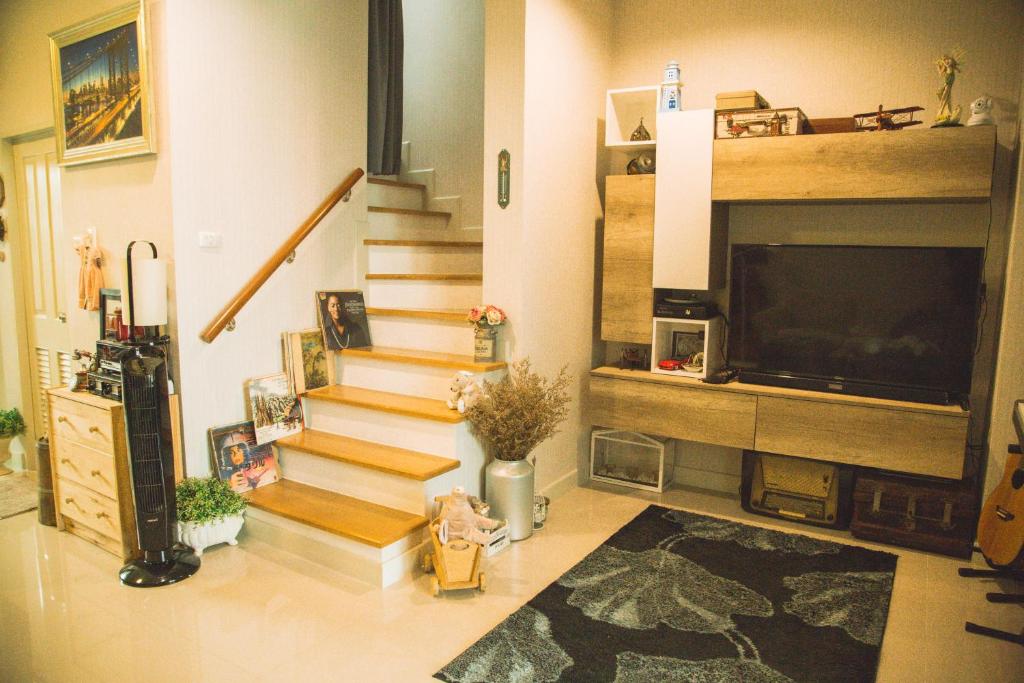 a living room with stairs and a flat screen tv at Autta house in Ban Lat Tanot