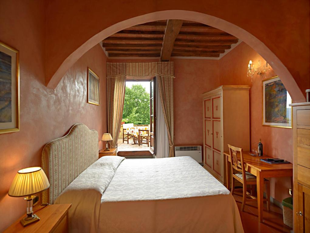 a bedroom with a bed and a desk and a window at B&B Palazzo Al Torrione 2 in San Gimignano