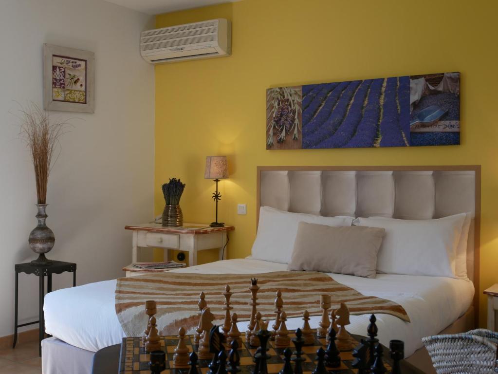 a room with a bed, chair, lamp and a painting on the wall at Hotel Les Ambres in Roussillon