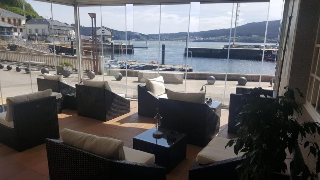patio con sillas y vistas al puerto deportivo en Hostal O Forno en Porto do Barqueiro