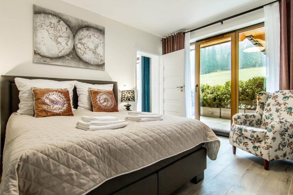 - une chambre avec un lit, une chaise et une fenêtre dans l'établissement Apartamenty Nosalowe Tarasy Zakopane, à Zakopane
