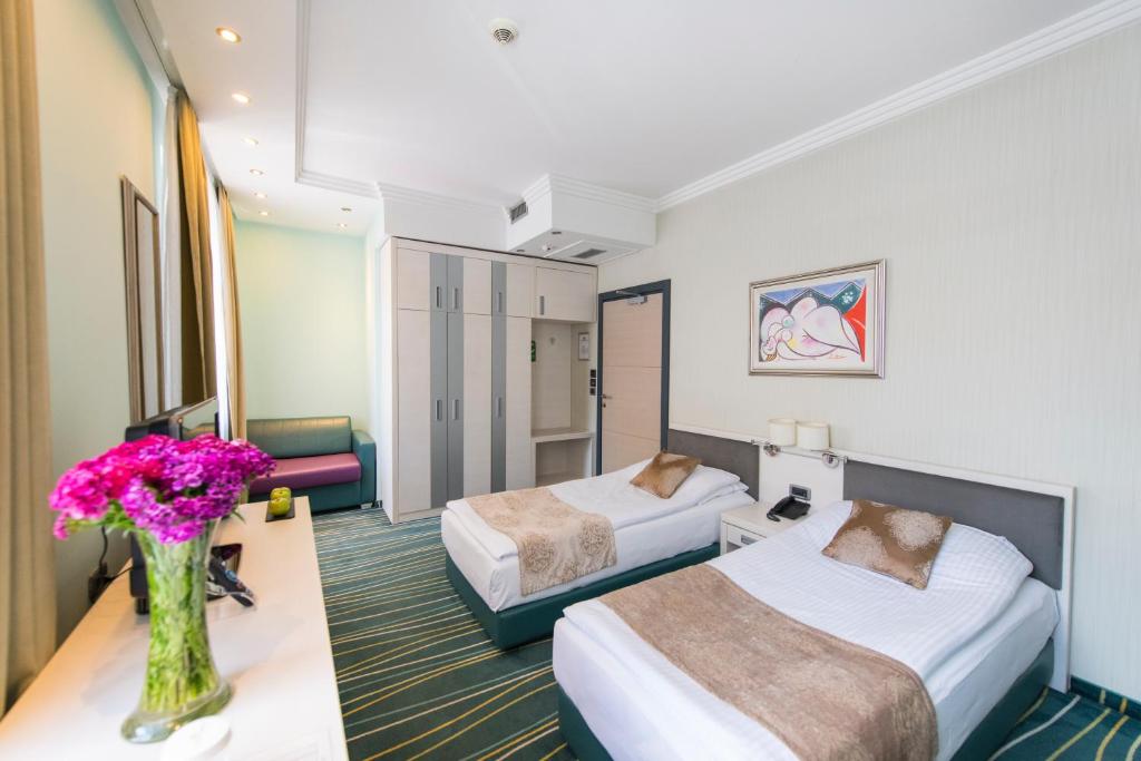 um quarto de hotel com duas camas e um vaso de flores em Kopernikus Hotel Prag em Belgrado