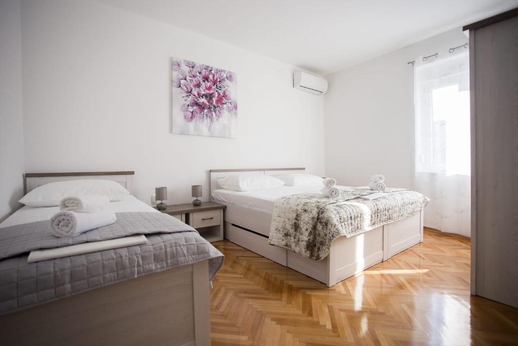 um quarto branco com 2 camas e uma janela em Apartman Leona em Kaštela