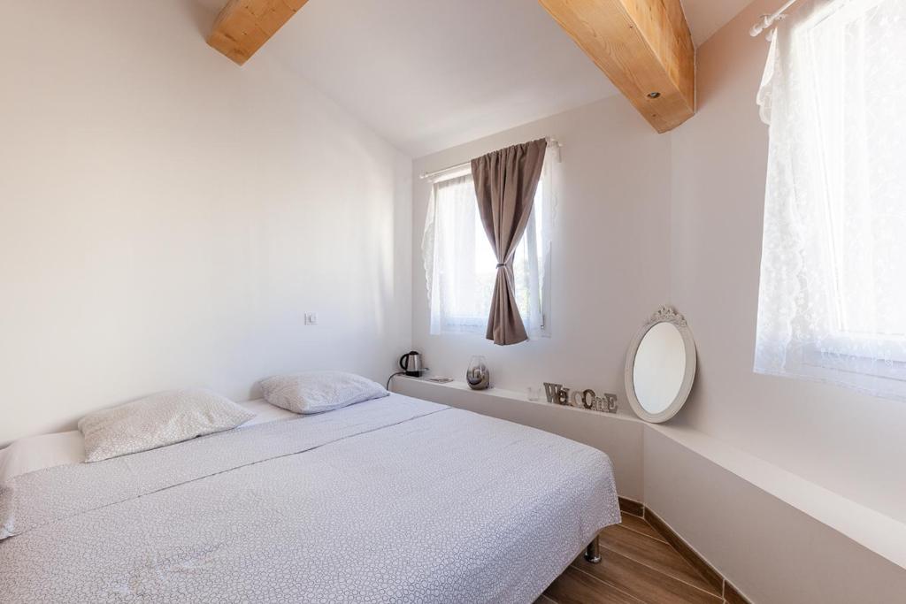 a white bedroom with a bed and a window at Alpinias Bed and Breakfast in Marseille