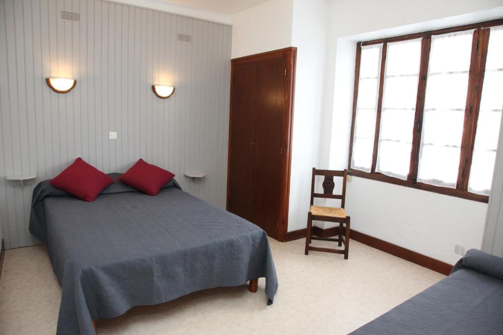 ein Schlafzimmer mit einem Bett mit roten Kissen und einem Stuhl in der Unterkunft Gîte altzia bas in Saint-Michel