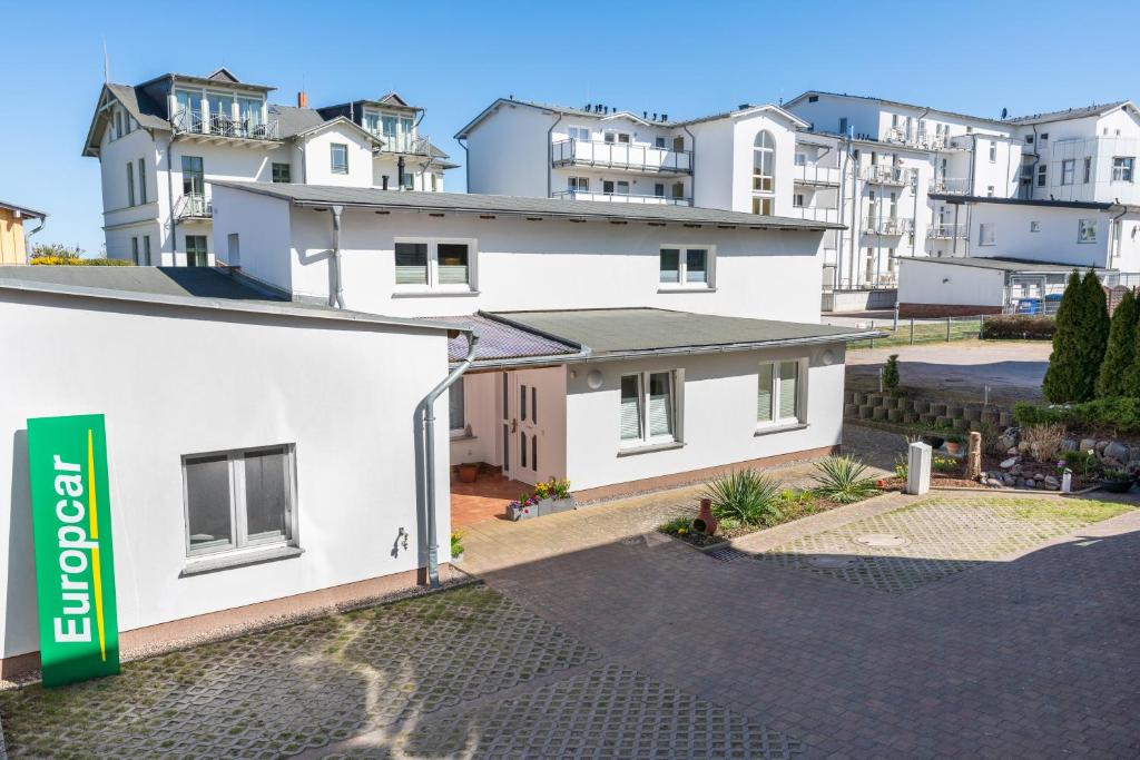 una vista de una casa blanca con casas en el fondo en Ferienwohnungen Wollenberg, en Ahlbeck