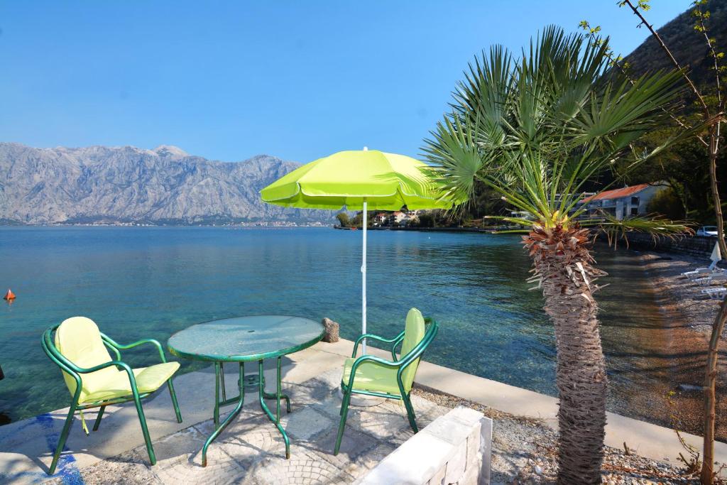 una mesa con sillas y una sombrilla junto al agua en Holiday Home Cattaro en Kotor