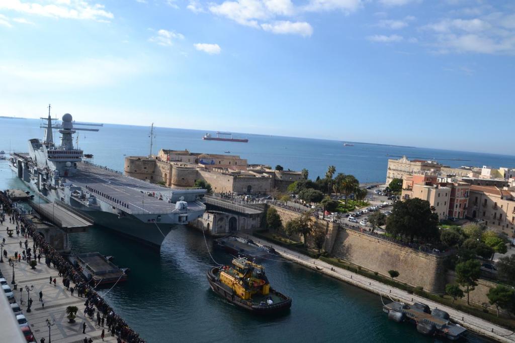 una barca in un fiume vicino a una nave da crociera di Hotel Virgilio a Taranto