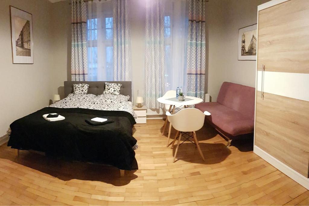 a bedroom with a bed and a chair and a couch at Czarna Owca- Pokoje Gościnne in Gniezno