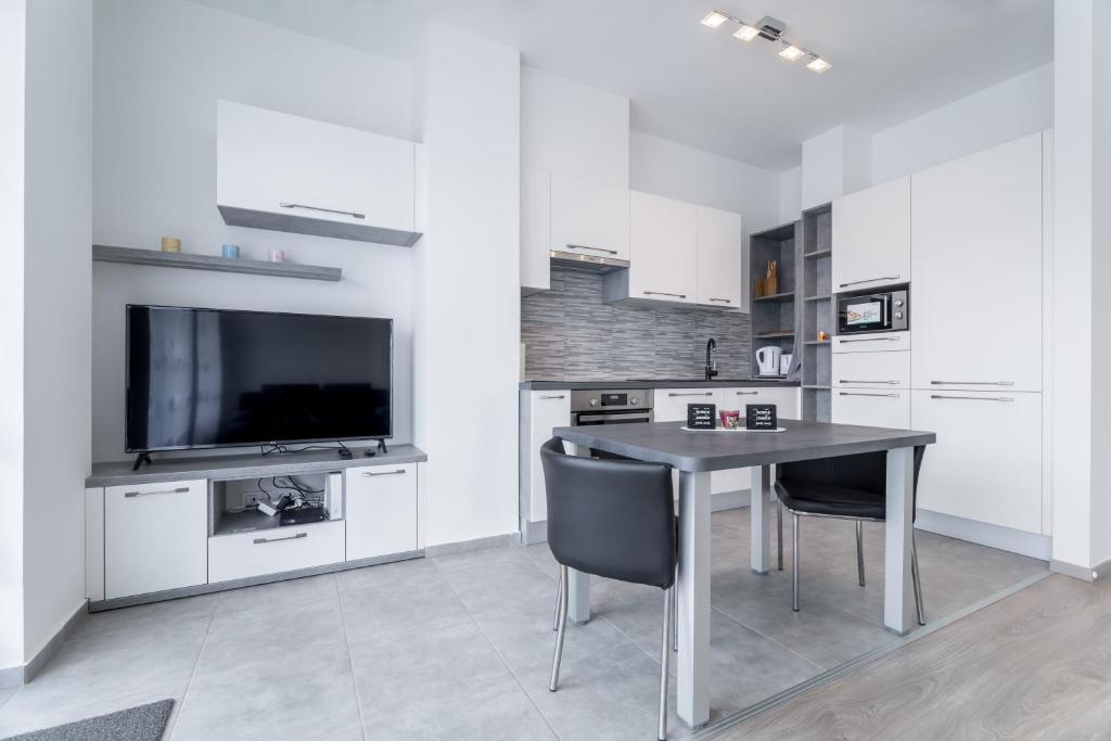 eine Küche mit einem Tisch und Stühlen sowie einem TV in der Unterkunft BpR CHIC White Home with Terrace & A/C & Garage in Budapest
