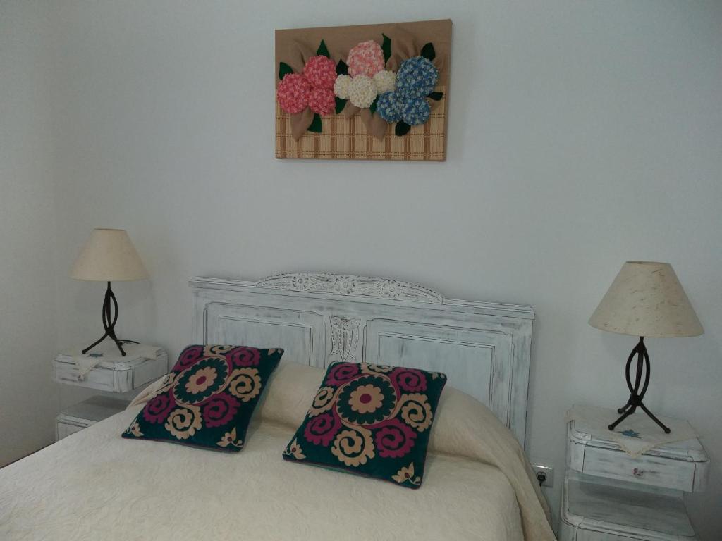 a bedroom with a white bed with two pillows at Casa da Rosarinha in Água de Alto