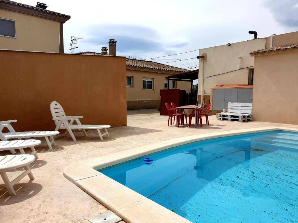 a swimming pool with chairs and a table and chairs at Caseta De L'avi in Camarles