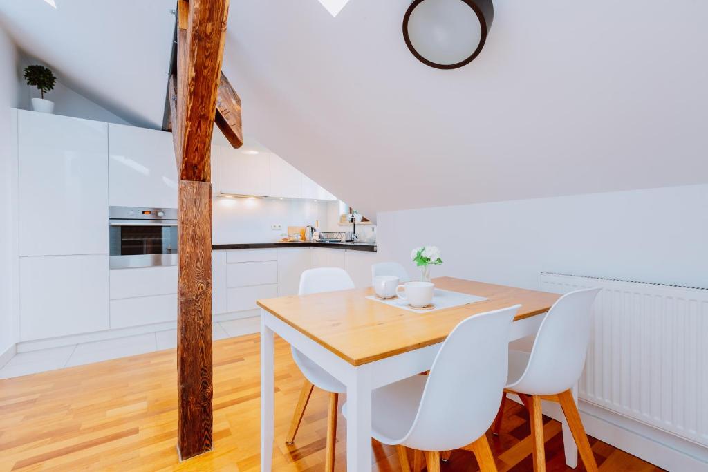 een keuken en eetkamer met een houten tafel en witte stoelen bij Atticus in Krakau