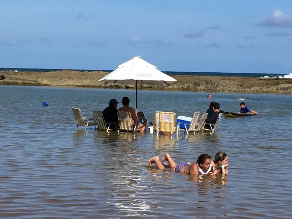 un grupo de personas nadando en un cuerpo de agua en Nannai Beira Mar Porto de Galinhas 307, en Porto de Galinhas