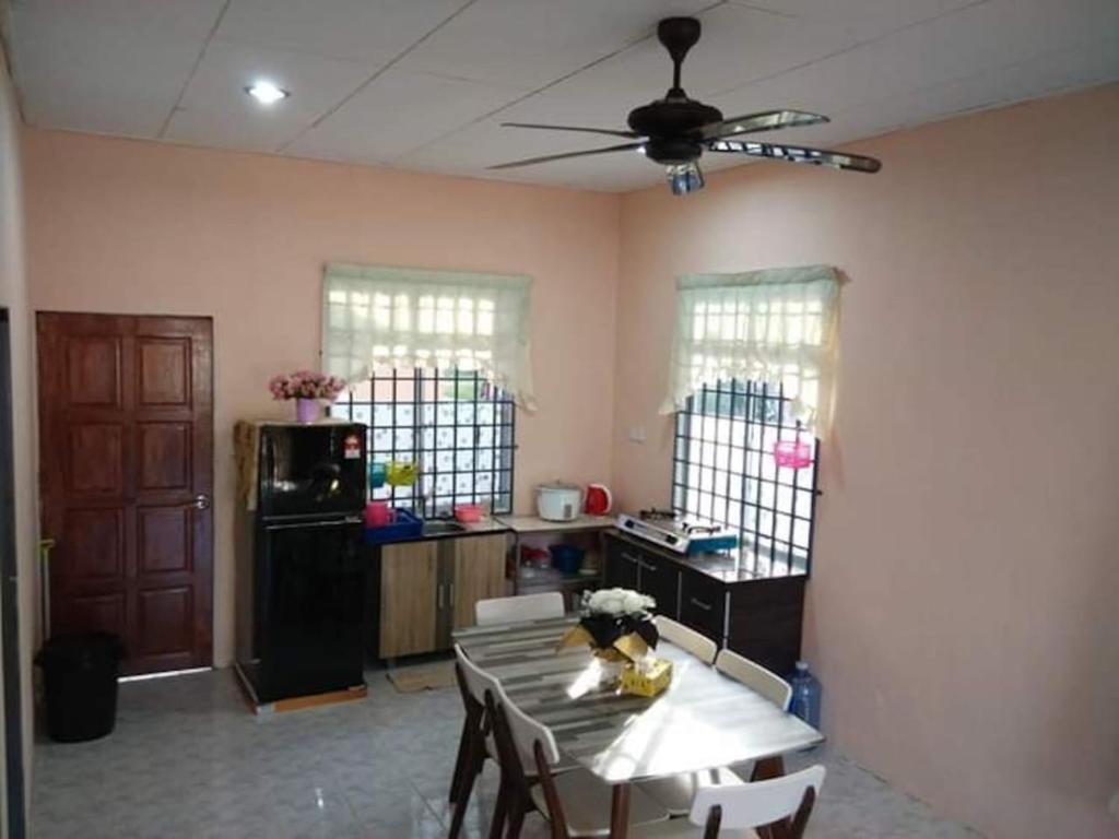 een woonkamer met een tafel en een plafondventilator bij HOMESTAY AQILAH PASIR PUTEH KELANTAN in Pasir Puteh