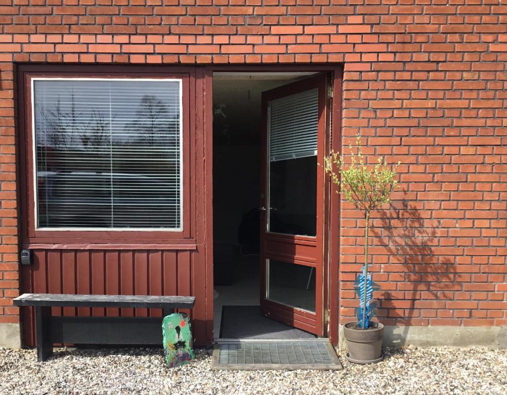 une porte ouverte menant à un bâtiment en briques avec un banc dans l'établissement Århus nord bed and breakfast, à Hinnerup