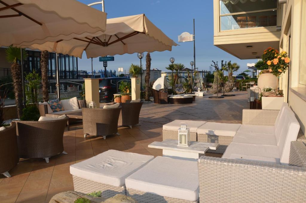 an outdoor patio with tables and chairs and umbrellas at Hotel Londra in Milano Marittima