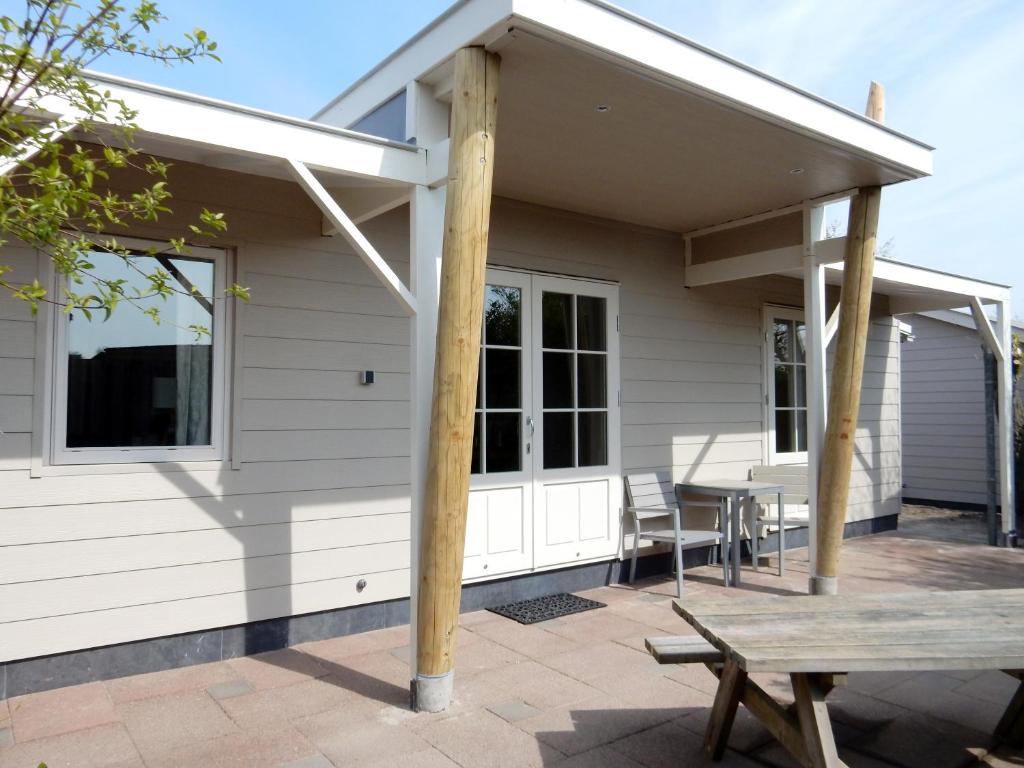 eine abgeschirmte Veranda mit einem Picknicktisch auf der Terrasse in der Unterkunft De Waterlelie in Renesse
