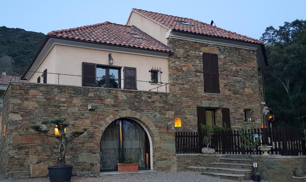 uma antiga casa de pedra com uma varanda no topo em Villa A funtanella em Patrimonio