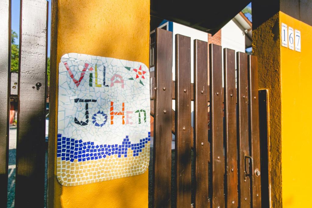 un cartello sul lato di un muro giallo di Villa Johen a Boicucanga