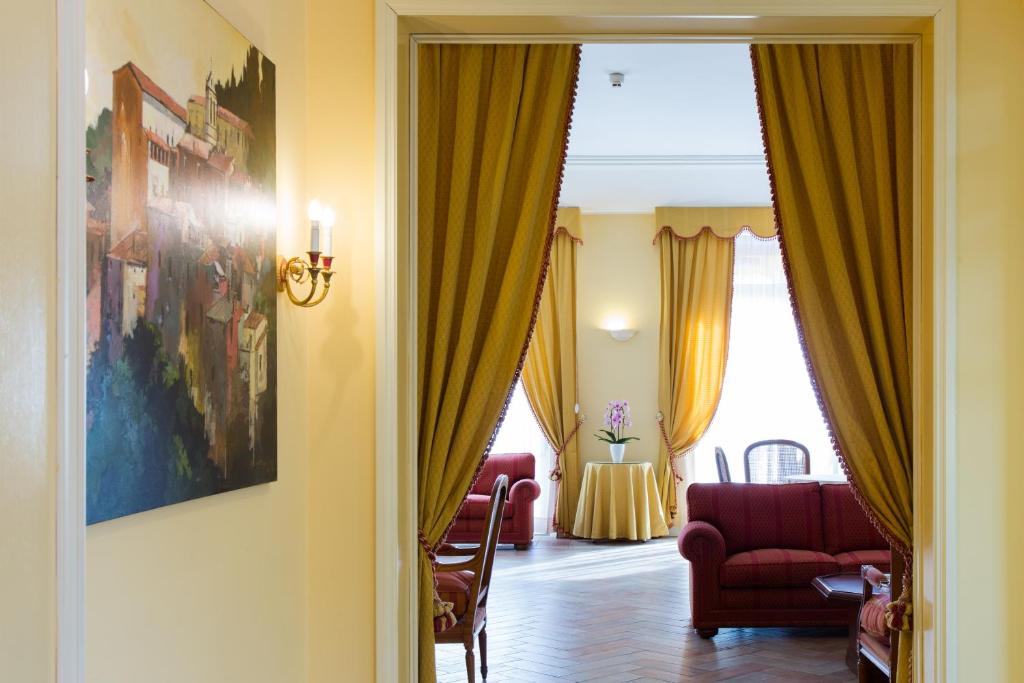 ein Wohnzimmer mit gelben Vorhängen und einem roten Stuhl in der Unterkunft Hotel Tuder in Todi