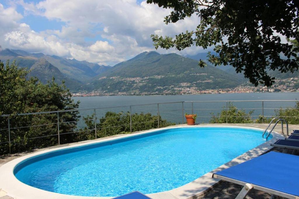 een zwembad met uitzicht op het water en de bergen bij Villa Erica con piscina privata sul lago di Como in Colico