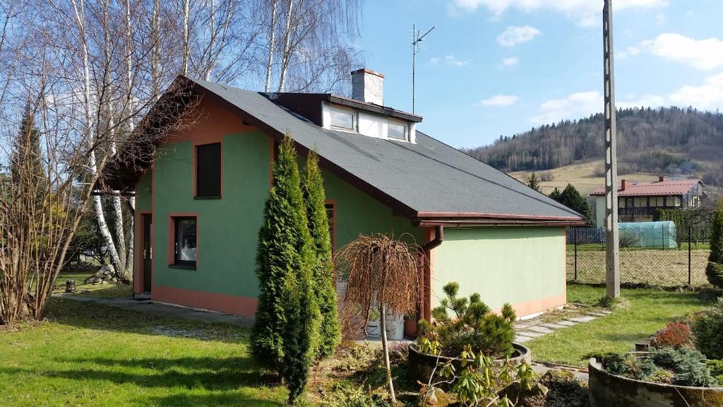 una pequeña casa verde con techo negro en Domek Pod Brzozami en Świnna