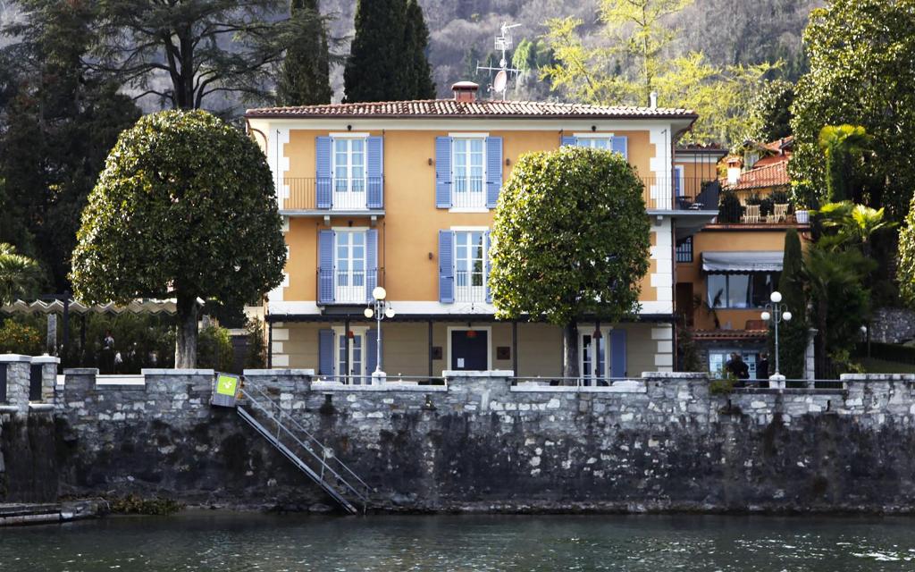a yellow house on the side of a river at Hotel Arancioamaro in Cannero Riviera