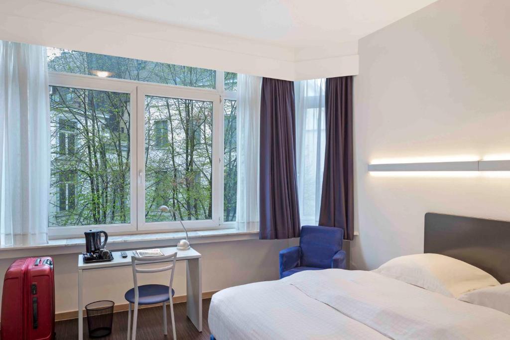 a hotel room with a bed and a desk and window at Argus Hotel Brussels in Brussels